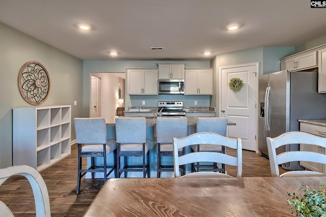 kitchen with visible vents, appliances with stainless steel finishes, dark wood-type flooring, and light stone countertops