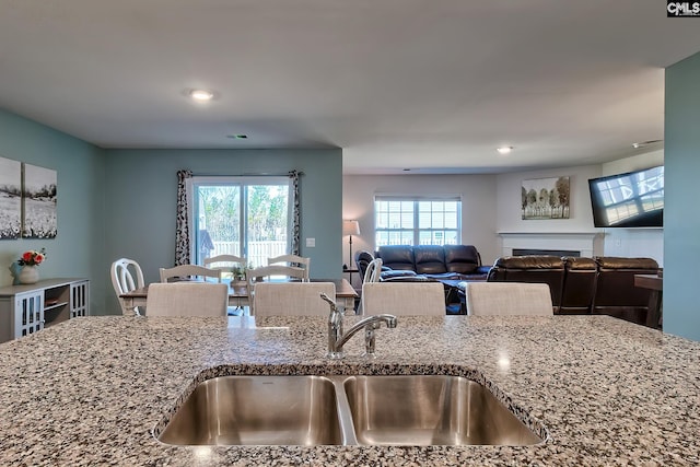 kitchen with a sink, stone counters, and plenty of natural light