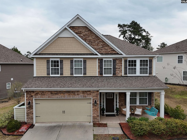 view of front facade with driveway, stone siding, a porch, roof with shingles, and a garage