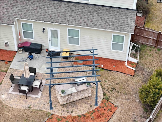 rear view of house featuring mansard roof, a patio area, roof with shingles, and fence