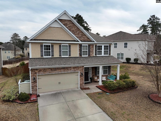 view of front of property with roof with shingles, an attached garage, covered porch, concrete driveway, and stone siding