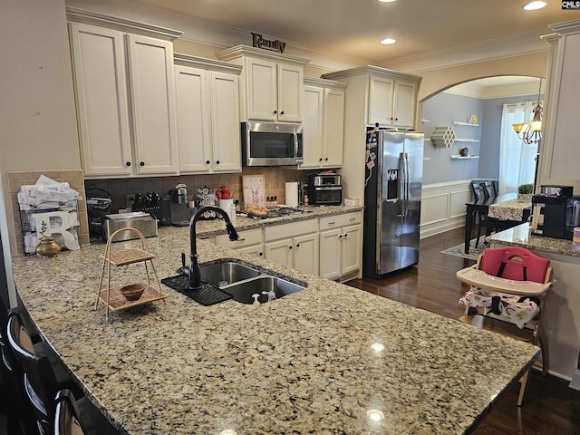 kitchen with dark wood-type flooring, a peninsula, arched walkways, stainless steel appliances, and a sink