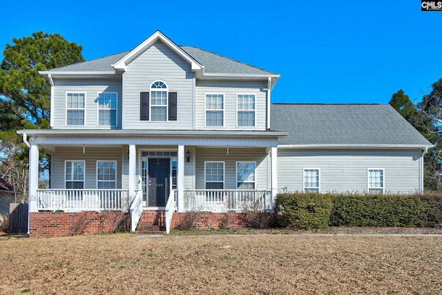 view of front of property with a front yard, covered porch, and roof with shingles