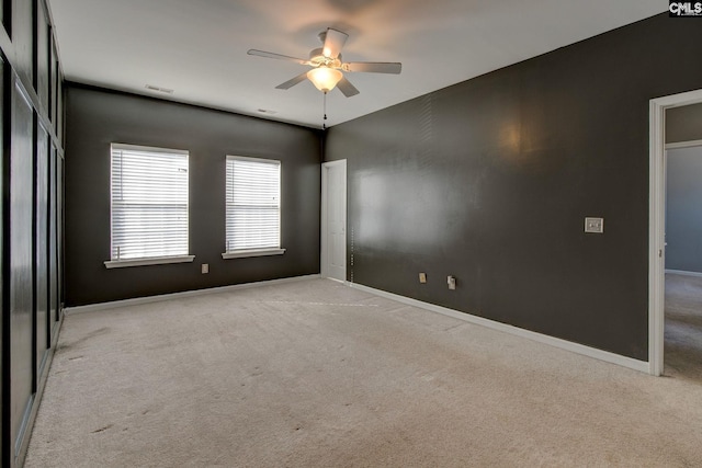 carpeted empty room featuring visible vents, a ceiling fan, and baseboards