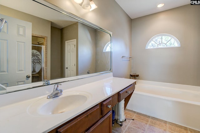 bathroom with a garden tub, vanity, and tile patterned flooring