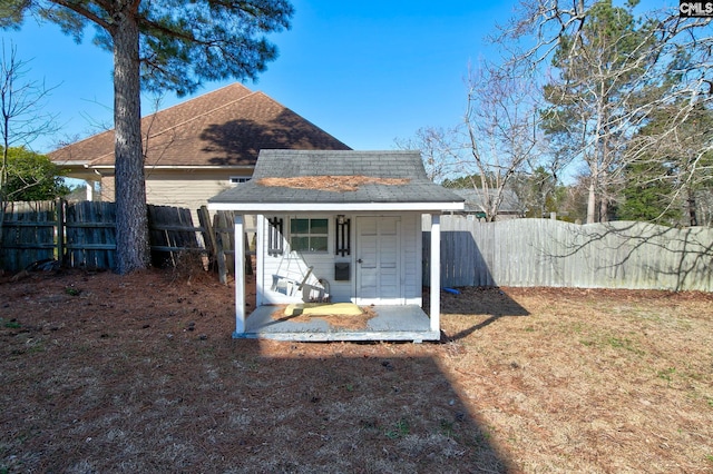 rear view of property with a shingled roof, an outdoor structure, and fence