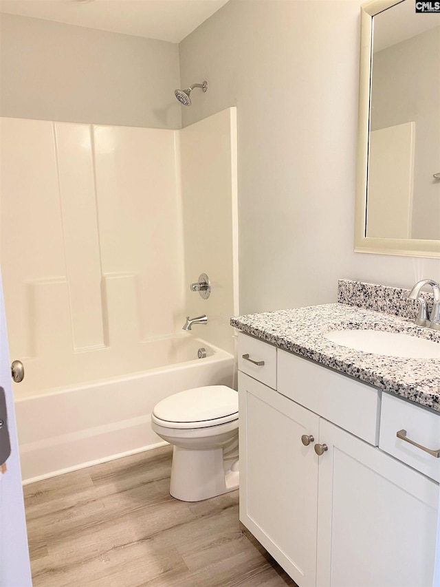 bathroom with vanity, toilet, wood finished floors, and shower / bathtub combination