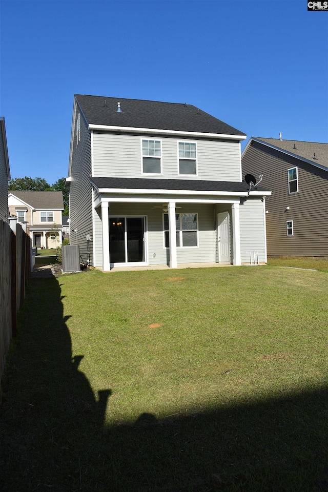 back of house with central AC unit, a lawn, and fence