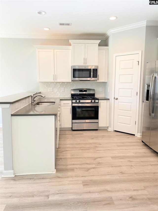 kitchen with visible vents, light wood-type flooring, white cabinets, stainless steel appliances, and a sink