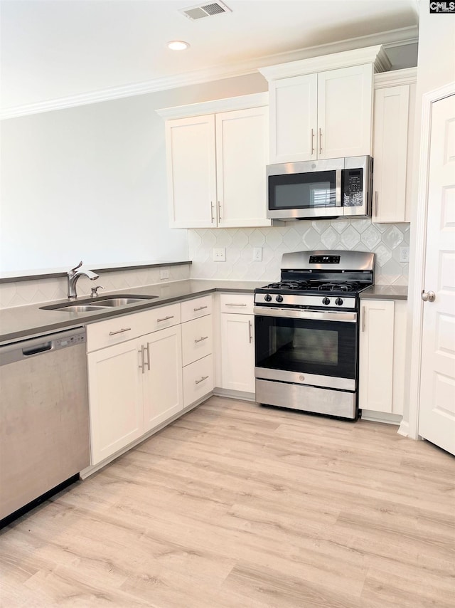 kitchen with a sink, decorative backsplash, appliances with stainless steel finishes, and ornamental molding