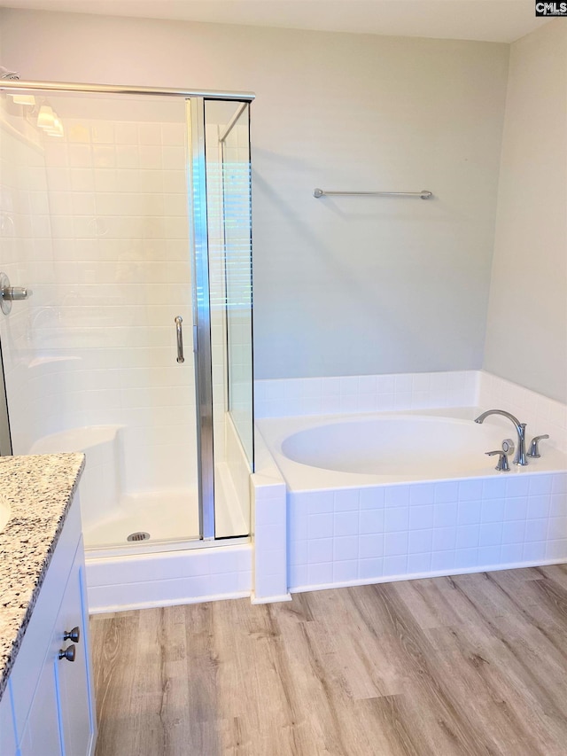 full bathroom featuring a stall shower, a garden tub, wood finished floors, and vanity