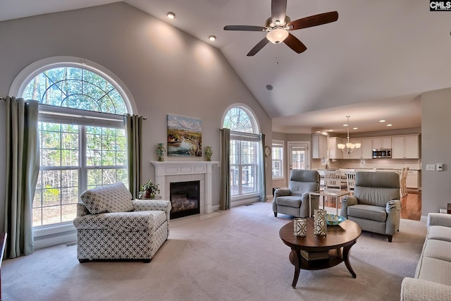 living room featuring light carpet, high vaulted ceiling, ceiling fan with notable chandelier, recessed lighting, and a tile fireplace