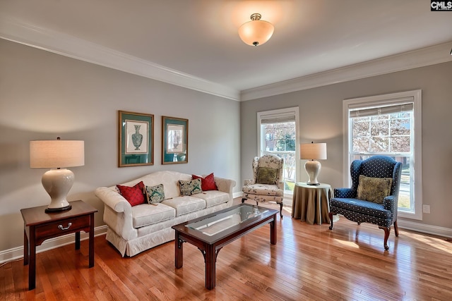 living area with baseboards, crown molding, and light wood finished floors