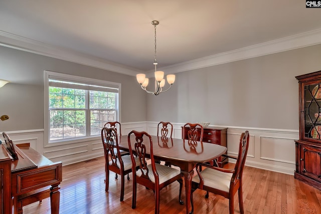 dining room featuring visible vents, light wood-type flooring, an inviting chandelier, and ornamental molding