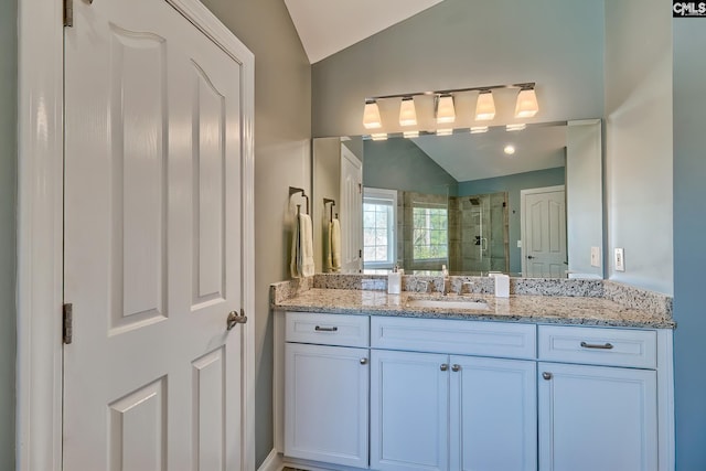 bathroom with vanity, vaulted ceiling, and a stall shower