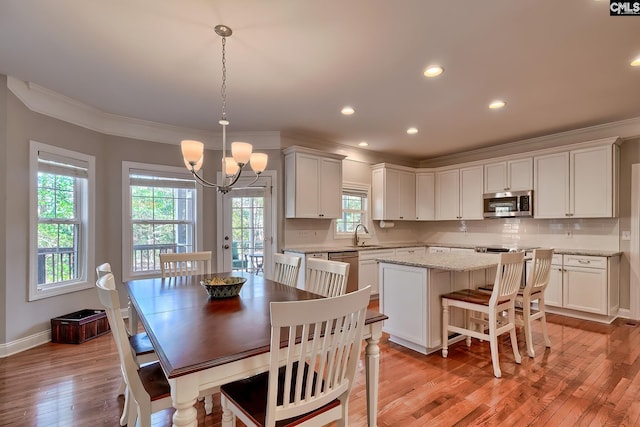 dining area featuring crown molding, baseboards, light wood-type flooring, and an inviting chandelier