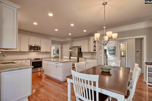 dining area with an inviting chandelier, crown molding, recessed lighting, and light wood-style floors