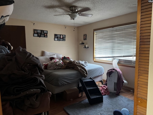 bedroom featuring ceiling fan, wood finished floors, and a textured ceiling