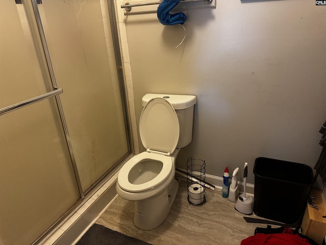 full bath featuring toilet, baseboards, and a stall shower