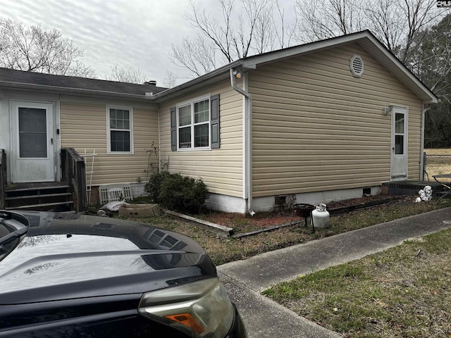 view of side of home with crawl space and entry steps