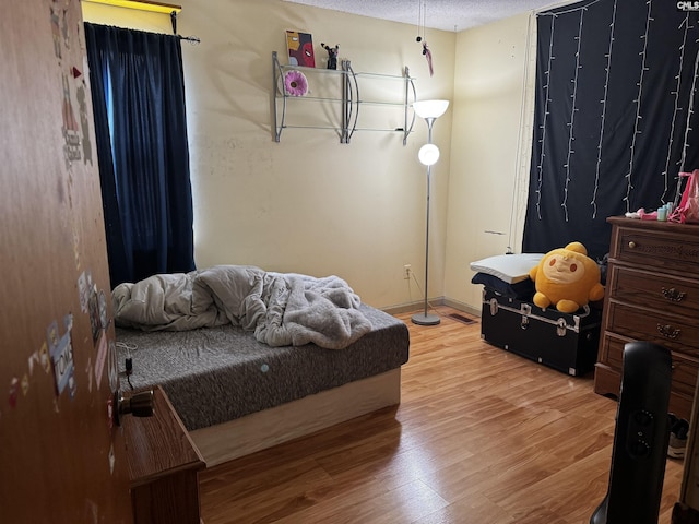 bedroom featuring wood finished floors, baseboards, and a textured ceiling