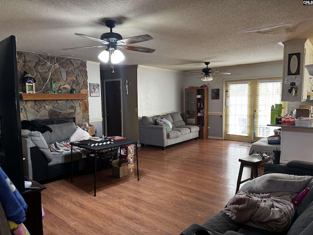 living area with crown molding, a fireplace, light wood finished floors, and a textured ceiling