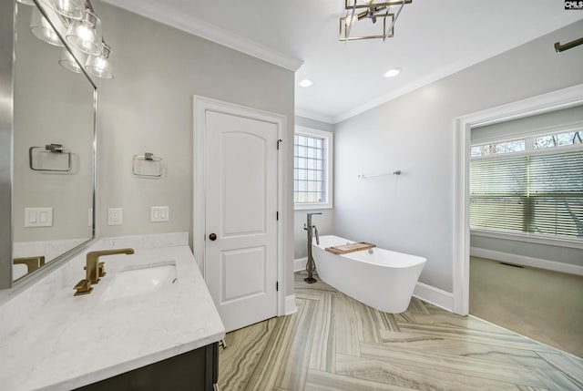 bathroom featuring a freestanding tub, visible vents, ornamental molding, baseboards, and vanity