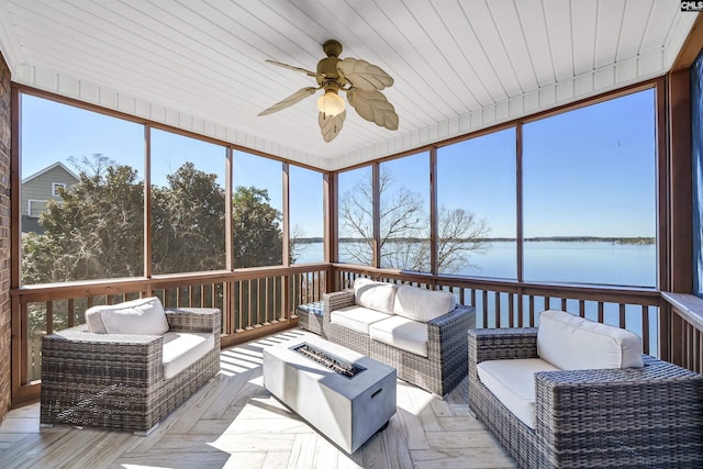 sunroom / solarium with a ceiling fan and a water view