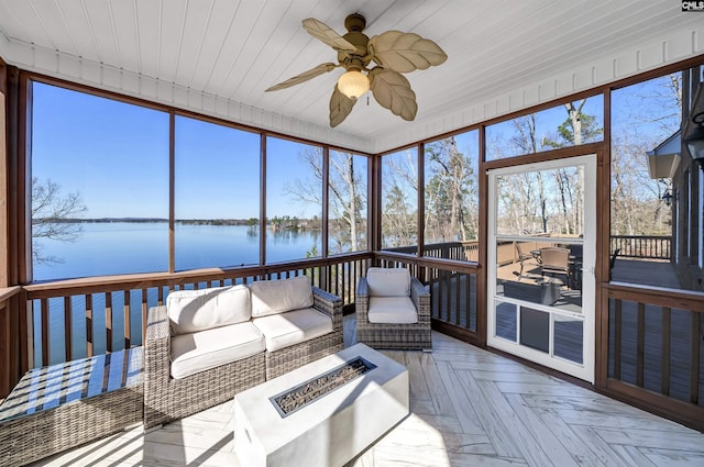 sunroom / solarium featuring a water view and ceiling fan