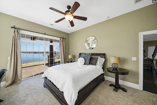 bedroom featuring visible vents, baseboards, a water view, carpet flooring, and a ceiling fan