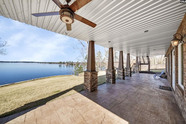 view of patio / terrace featuring stairs, a ceiling fan, and a water view