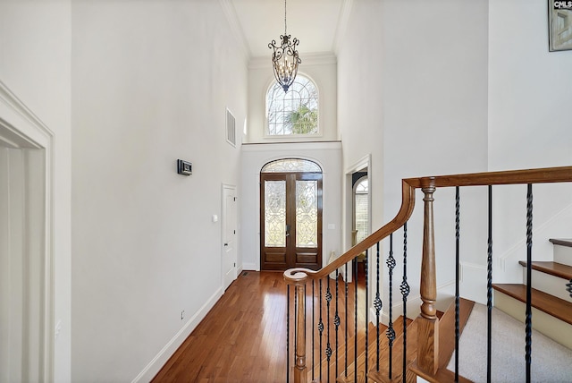 foyer entrance featuring plenty of natural light, ornamental molding, stairs, and hardwood / wood-style flooring