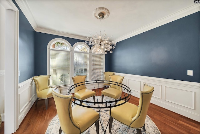 dining space with a wainscoted wall, crown molding, an inviting chandelier, and wood finished floors