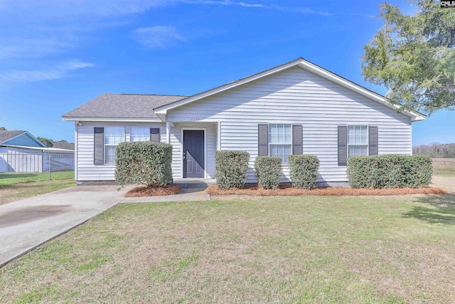 ranch-style house with a shingled roof, a front yard, and fence