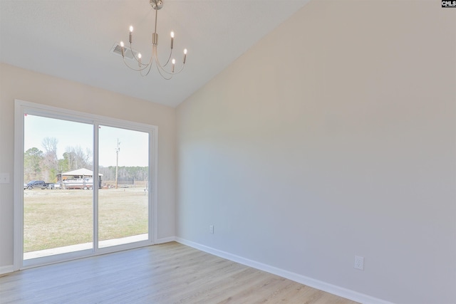 empty room featuring light wood-style flooring, baseboards, an inviting chandelier, and vaulted ceiling