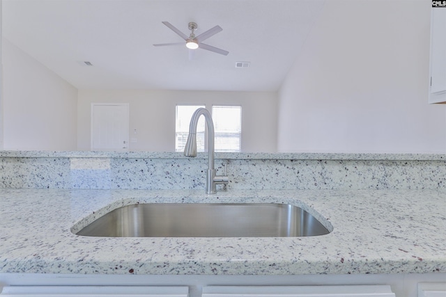 details with visible vents, a sink, white cabinetry, light stone countertops, and ceiling fan