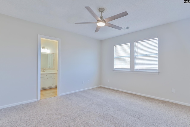 unfurnished room with visible vents, light colored carpet, baseboards, and ceiling fan