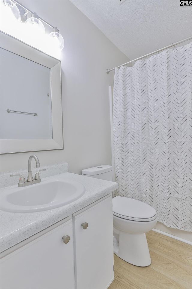 full bathroom featuring vanity, a shower with shower curtain, wood finished floors, a textured ceiling, and toilet