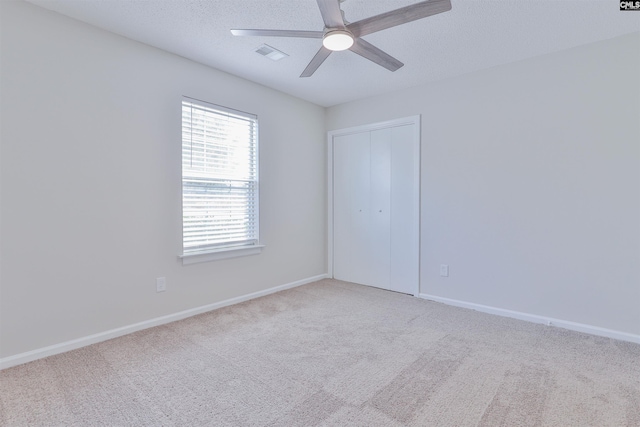 unfurnished room with carpet, visible vents, baseboards, ceiling fan, and a textured ceiling