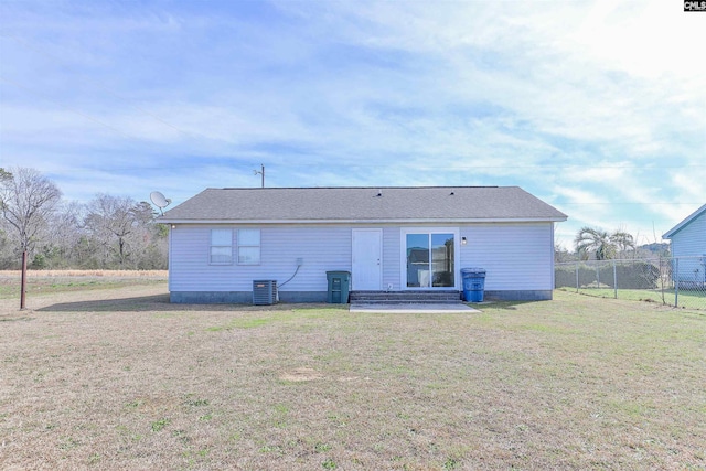 rear view of house with central AC unit, a lawn, entry steps, and fence