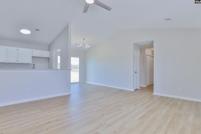 unfurnished living room featuring visible vents, lofted ceiling, a sink, light wood-style floors, and ceiling fan with notable chandelier