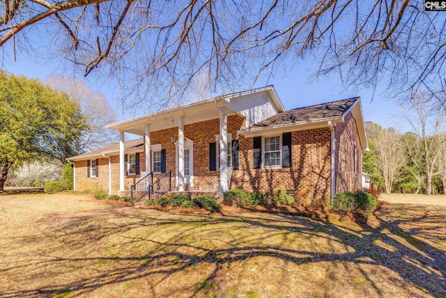 view of front of house with brick siding, a porch, and a front lawn