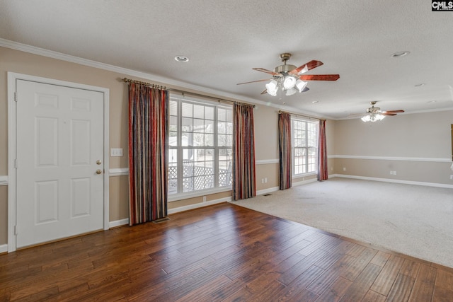 spare room with a textured ceiling, wood finished floors, baseboards, and ornamental molding