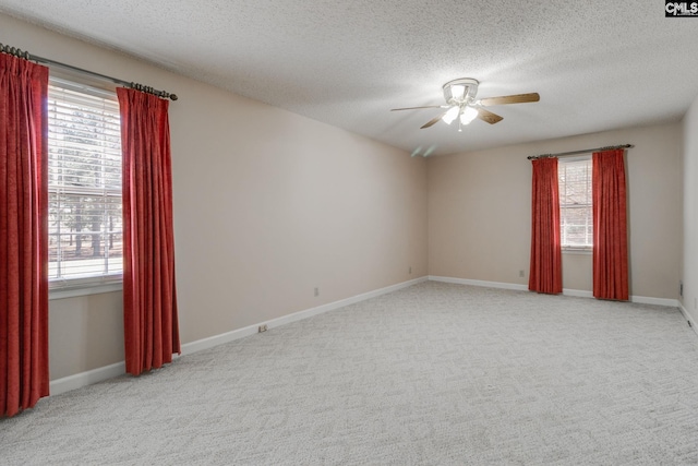 unfurnished room featuring baseboards, light carpet, a textured ceiling, and a ceiling fan