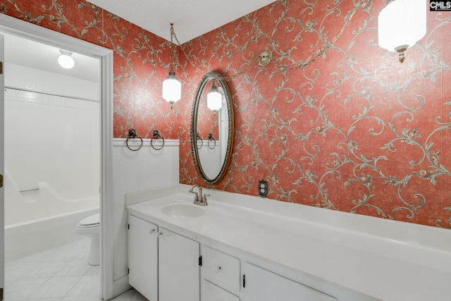 bathroom with vanity, wallpapered walls, tile patterned flooring, wainscoting, and toilet