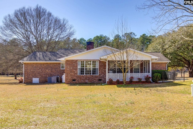 rear view of house featuring a yard, crawl space, brick siding, central AC unit, and a chimney