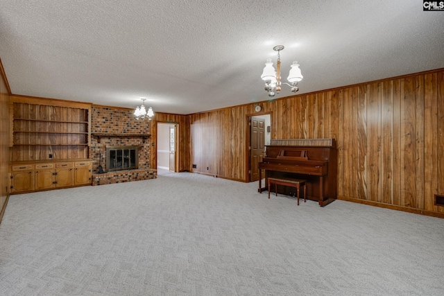 carpeted living area with a textured ceiling, a brick fireplace, a chandelier, and wooden walls