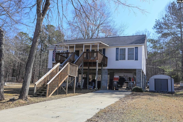 view of front facade with a storage unit, a porch, an outdoor structure, concrete driveway, and a carport