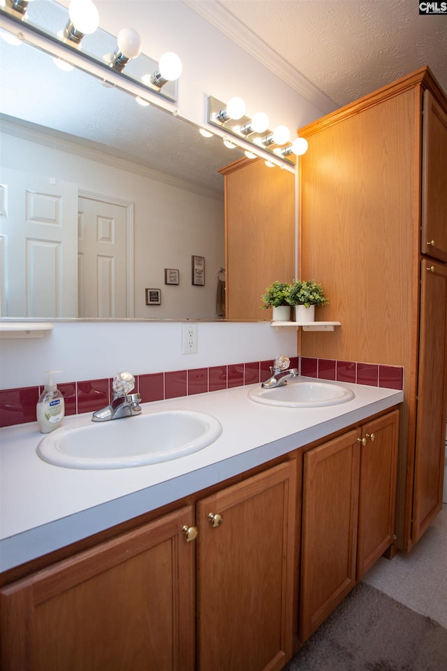 bathroom featuring a sink, a textured ceiling, ornamental molding, and double vanity