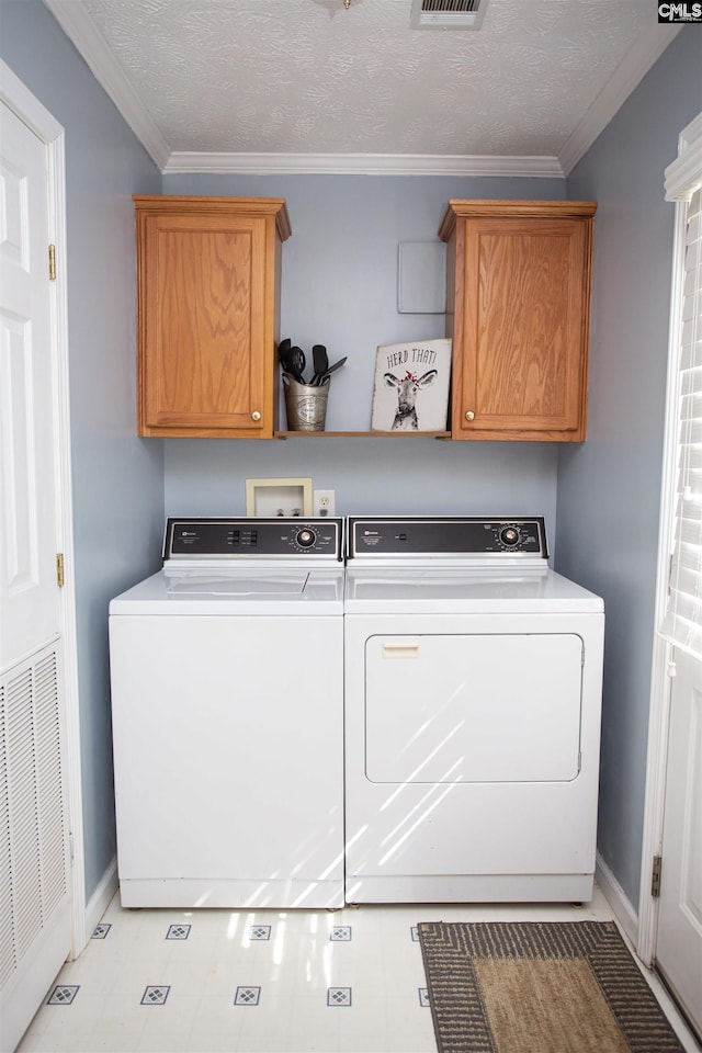 laundry room with cabinet space, visible vents, washer and dryer, and crown molding